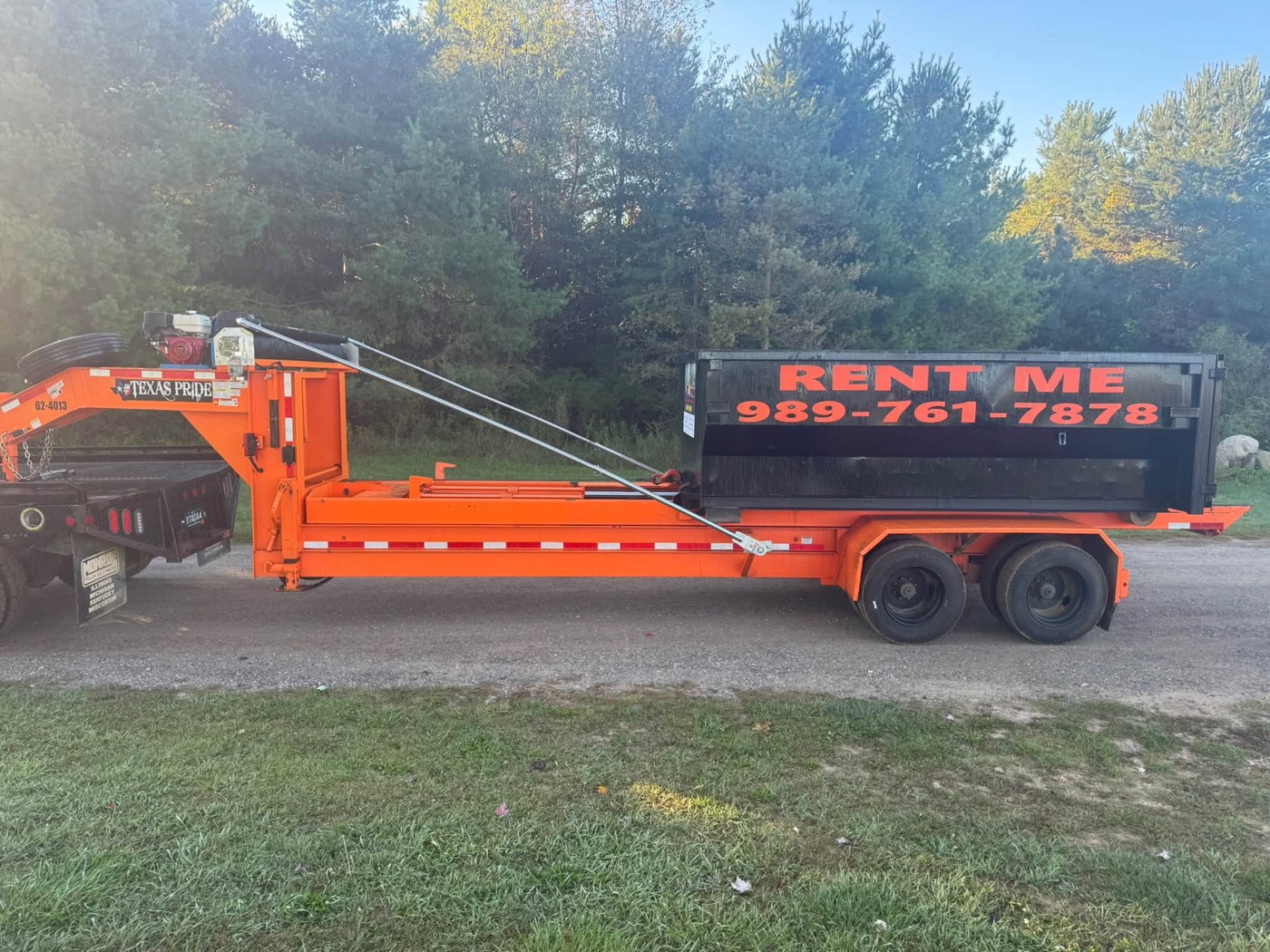 Black dumpster loaded on a trailer, ready for delivery